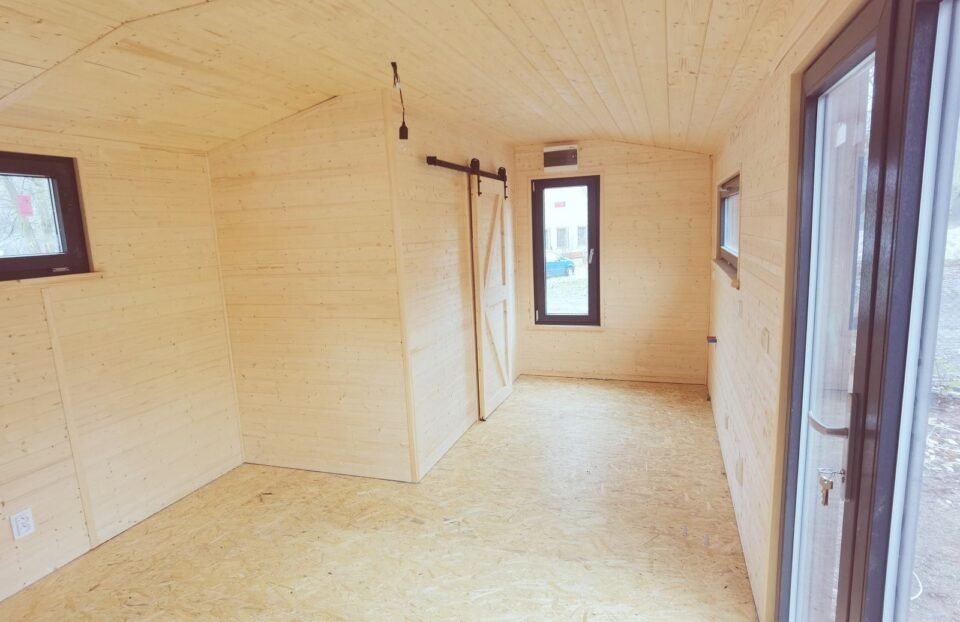 Interiér malé dřevěné chatky s posuvnými dveřmi.