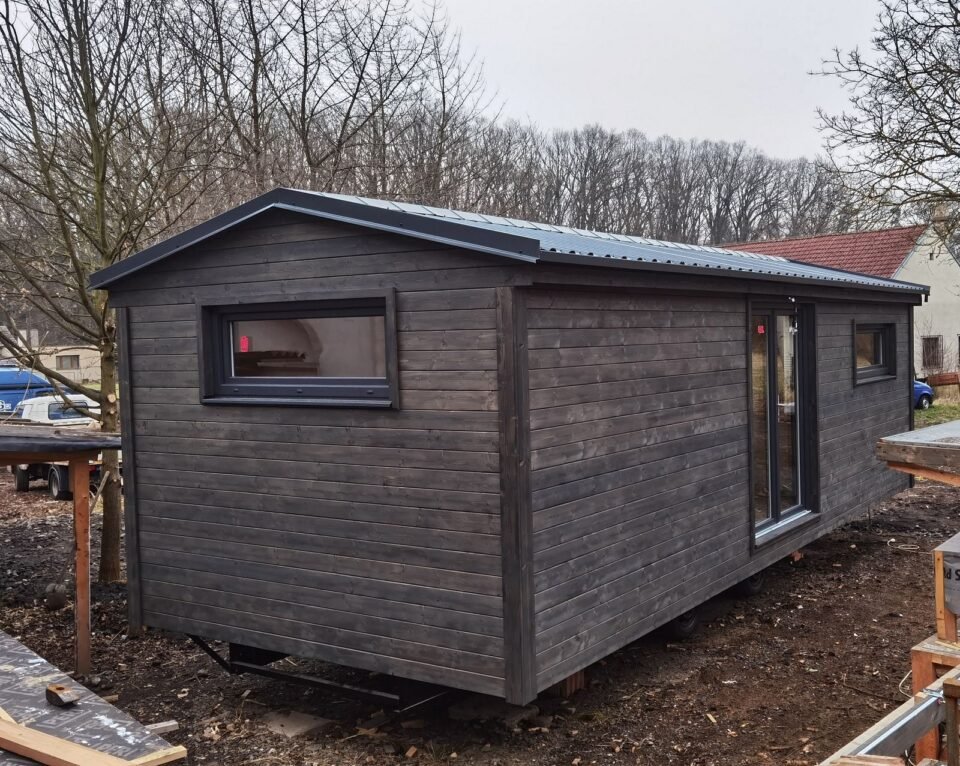 Dřevěná chata na zahradě se stromy v pozadí.