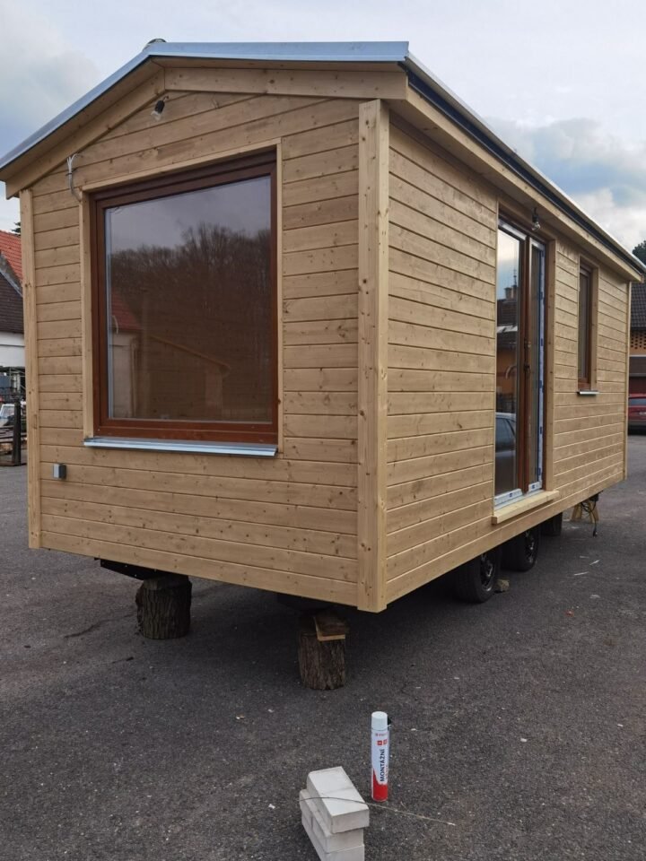 Dřevěný mobilní dům na kolech v exteriéru.