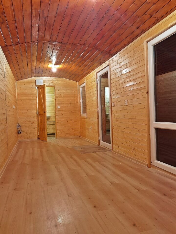 Dřevěný interiér s otevřenými dveřmi a okny.