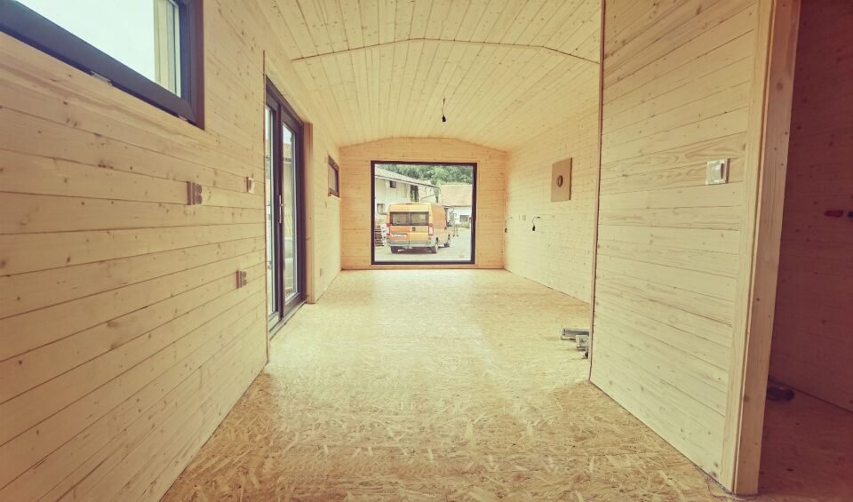 Interiér dřevěného tiny domu, pohled ven na dodávku.