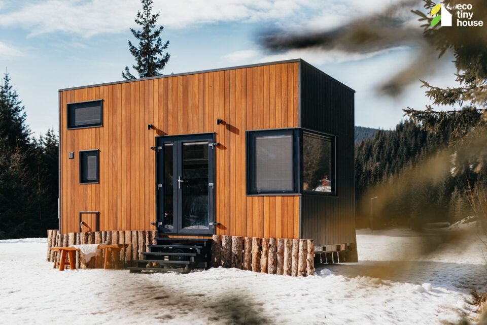 Dřevěn&yacute; tiny house ve sněhu v lese.